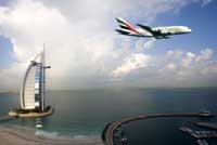 An Airbus A380 flies over Dubai's beachfront in full Emirates livery