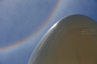 Nose of an Airbus A330-300 shot while lying on the ground with a sun ring in the sky.