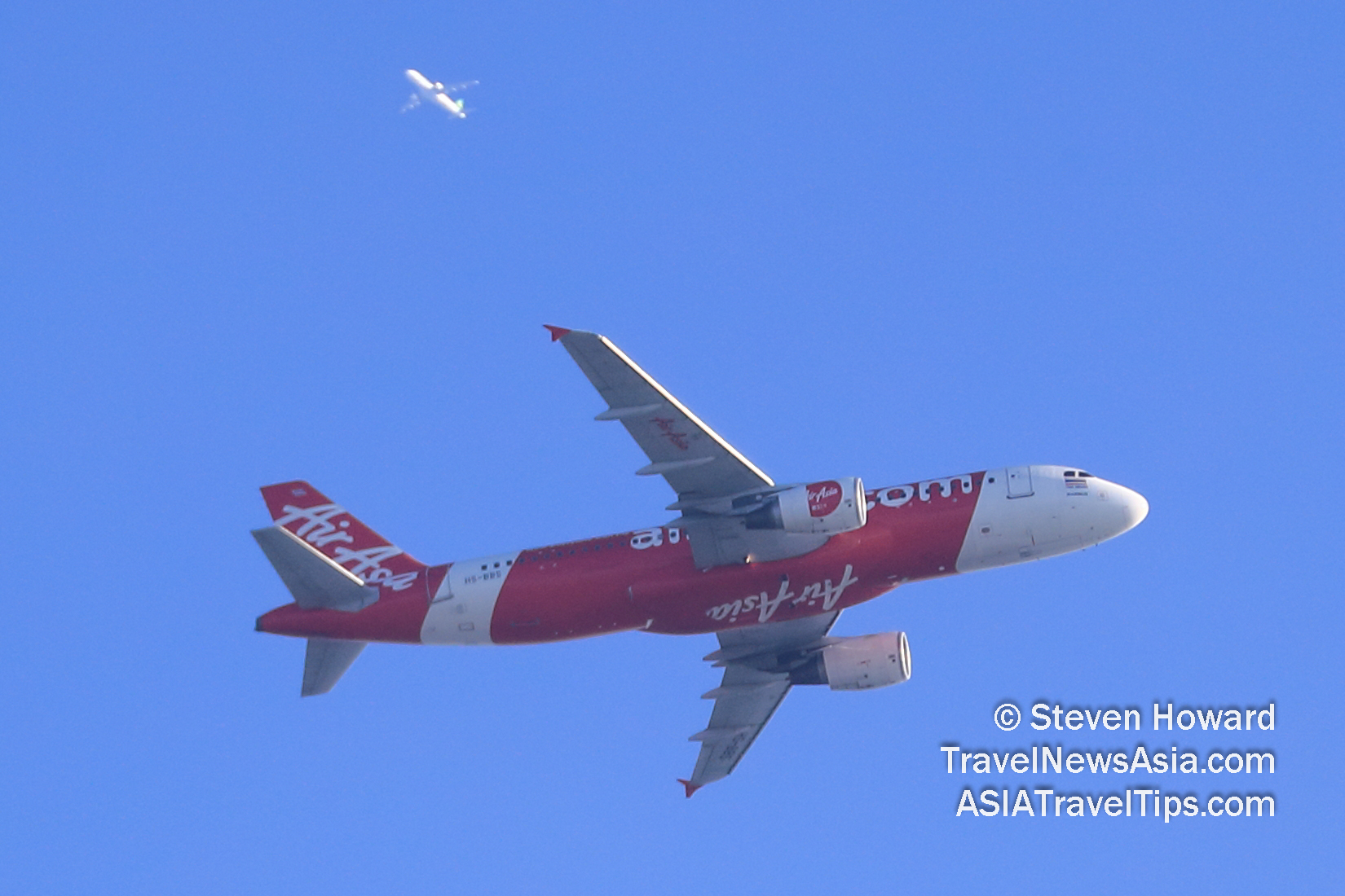 AirAsia Airbus A320 flying overhead with another aircraft above, much higher in the sky above Bangkok, Thailand. Picture by Steven Howard of TravelNewsAsia.com Click to enlarge.