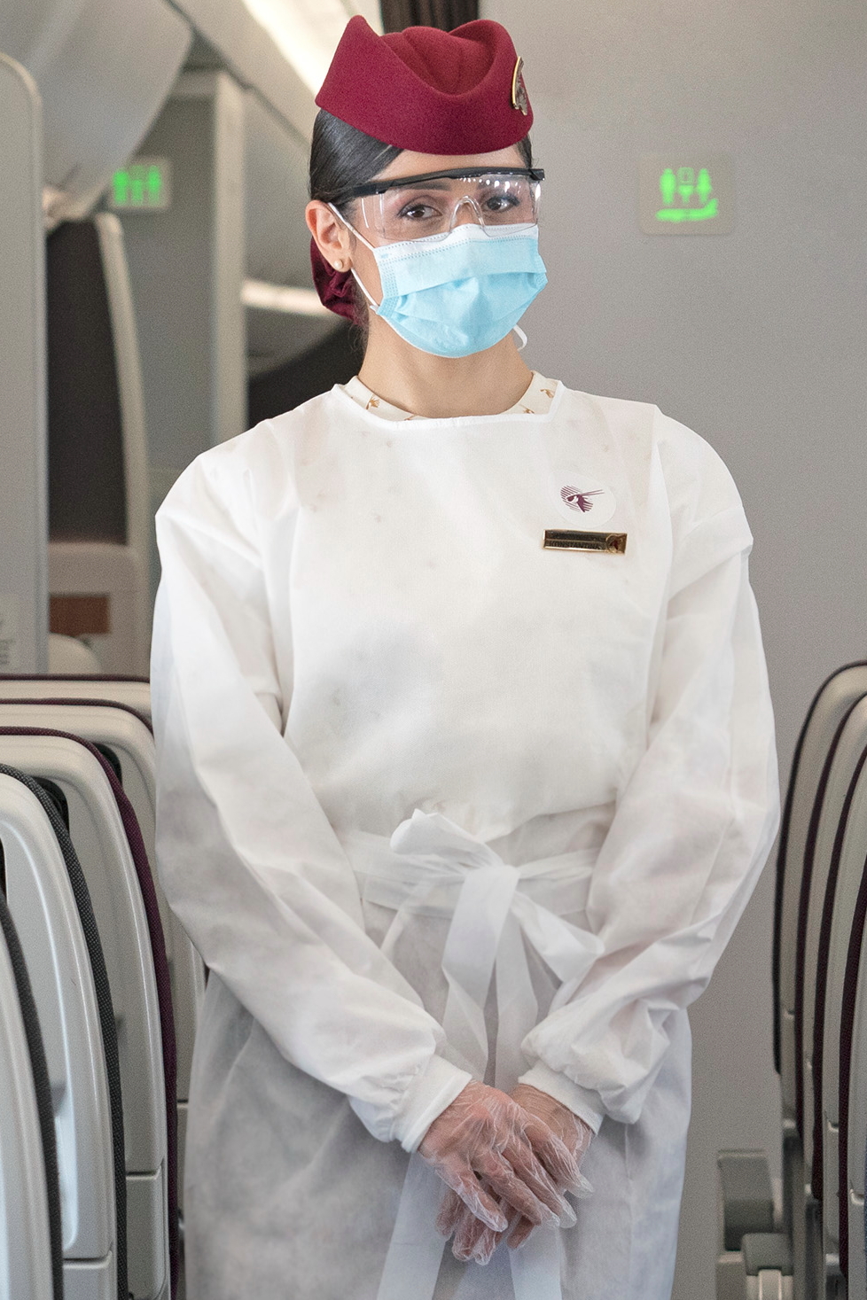 Qatar Airways has introduced new disposable protective gowns for cabin crew that are fitted over their uniforms, in addition to safety glasses, gloves and a mask. The new branded gowns are personalised with Qatar Airways’ logo imprinted on the top left corner. Click to enlarge.