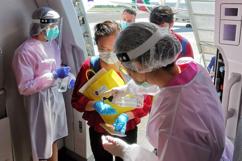 Thai Airways cabin crew wear PPE as Thai citizens board one of the many repatriation flights that the airline has operated in recent days and weeks.. Click to enlarge.
