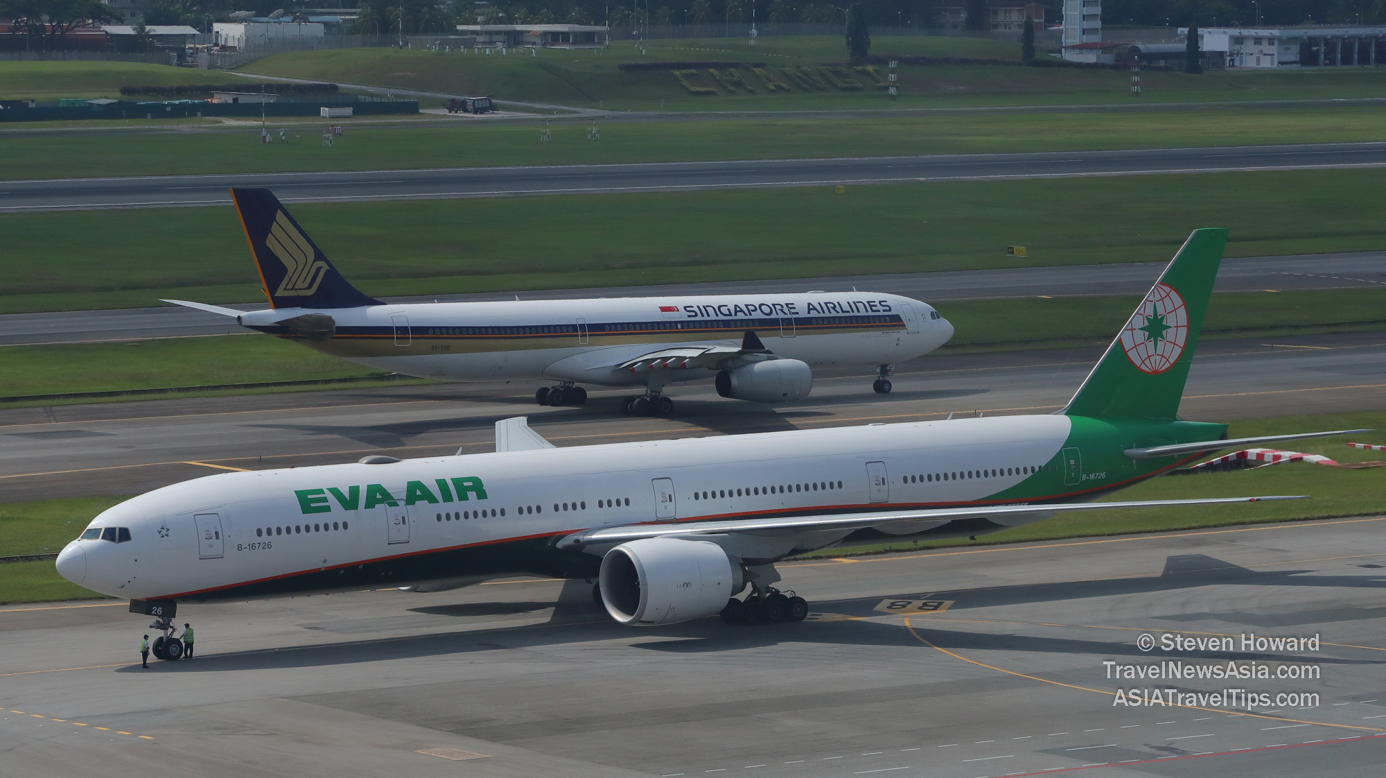 EVA Air Boeing 777-300ER reg: b-16726 and Singapore Airlines aircraft at Changi Airport. Picture by Steven Howard of TravelNewsAsia.com from a Runway Room at Crowne Plaza Changi Airport Hotel. Click to enlarge.