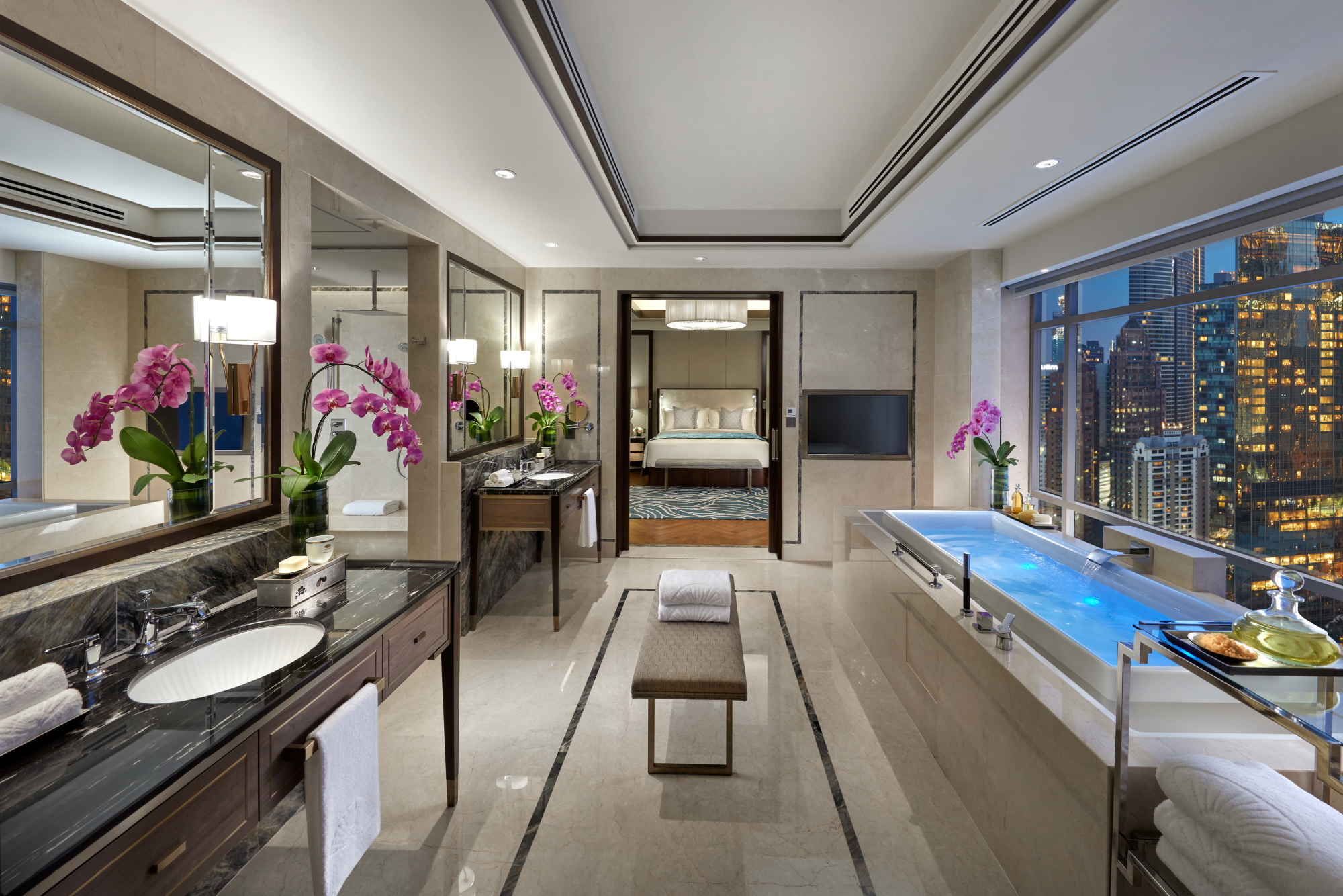 The marble master bathroom of the Presidential Suite at the Mandarin Oriental Kuala Lumpur features an expansive infinity edge bath that overlooks the city lights and features his and her vanity units and showers. Click to enlarge.